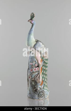 Figurine de paon, chinoise, dynastie Qing 1644–1911, XIXe siècle. Sculpture en porcelaine de couleur céramique représentant un paon avec ornement en plumes de paon, images d'oiseaux, de prunier et de tronc d'arbre avec des fleurs. Hauteur 54,5 cm, largeur 14,0 cm, profondeur 12,5 cm, poids 2,9 kg., sculpture en céramique d'un oiseau perché sur une base texturée, montrant un long cou et une crête verticale ; l'oiseau affiche une palette pastel avec des tons bleu pâle et vert sur son corps, des teintes rosâtres sur sa poitrine et son visage, et un ombrage sur son bec et ses ailes. L'aile présente des plumes ressemblant à des écailles qui se chevauchent en bleu et en sourdine Banque D'Images