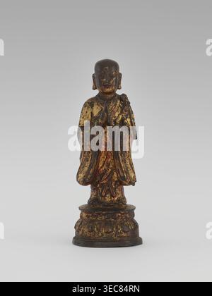 Moine, chinois, figure d'arhat de Luohan, moine, sauge; art bouddhiste ; iconographie du trône du lotus ; dynastie Qing 1644–1911, XIXe siècle ; sculpture, figurine ; hauteur 24,7 cm, Une petite statue debout d'une figure en rodage sur une base arrondie, représentée sur un fond gris neutre ; la figure a une tête arrondie et les mains tenues ensemble près de la poitrine, et la robe et la base montrent des zones usées avec des tons or et brun foncé visibles avec des traces de rouge, donnant un aspect vieilli et vieilli. Banque D'Images