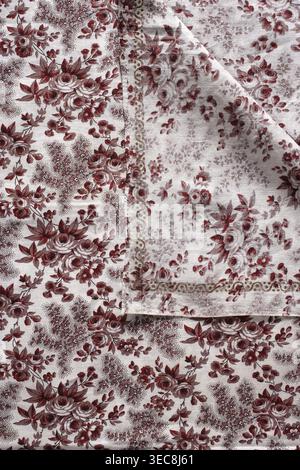 Taie d'oreiller. Taie d'oreiller en toile de coton imprimée avec motif floral sur un fond blanc : brins imprimés disposés en diagonale en grappes plus petites et plus grandes, y compris des roses, des oubliettes et des clochettes. Autour des bords un serpent enroulé imprimé avec trois points dans les virages. Couleurs : marron clair et Bordeaux. XVIIIe siècle, Province de Silésie 1742-1918. Hauteur 84 cm, largeur 76 cm., l'image montre un tissu à motifs avec un motif floral répétitif dans les tons rouges et blancs, avec des grappes de roses et de feuilles ; un coin du tissu est replié, révélant le dessous avec une version légèrement délavée Banque D'Images