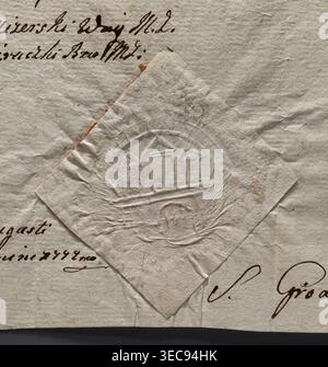 Sceau rond à empreinte sèche de la ville de Żarki, voïvodie de Częstochowa. Représente le mur de la ville avec une porte fermée et trois tours avec des toits coniques, la tour du milieu plus grande. Scellé sur un document. Inscription : sceau de la ville de Żarki. 1772, Pologne. Fabricant : Witold Żurakowski ( ?-1927), Un gros plan de papiers vieillis se chevauchant avec des surfaces texturées et froissées montrant une pièce en forme de losange superposée sur une feuille plus grande ; les papiers affichent une gamme de tons blanc cassé, beige et clair avec des taches brun subtiles et des ombres grises pâles ; la pièce en losange a un motif circulaire en relief avec relief Banque D'Images