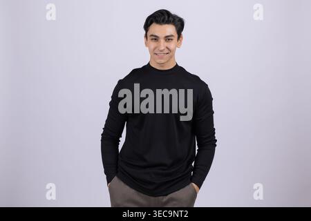Jeune homme détendu avec les mains dans les poches souriant à la caméra Banque D'Images