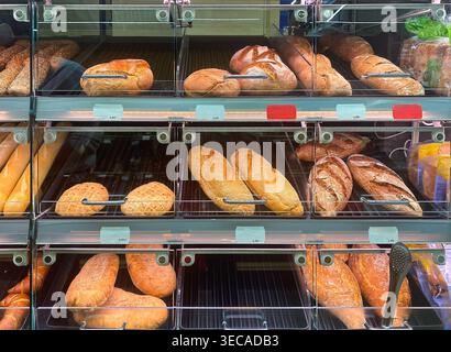 Divers types de pain, y compris les baguettes, les petits pains et les pains, sont exposés sur les étagères d'une boulangerie ou d'une épicerie Banque D'Images