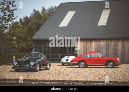 Trois véhicules Porsche vintage sont exposés devant une structure contemporaine, mettant en valeur le design automobile Banque D'Images
