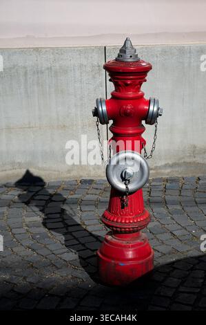 Visegrad, Hongrie - 18 avril 2026 : une bouche d'incendie rouge ornée se dresse sur une rue pavée pendant la lumière de l'après-midi dans le centre-ville historique. Banque D'Images