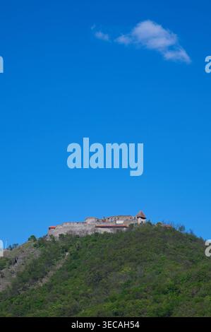 Visegrad, Hongrie - 18 avril 2026 : vue verticale du Haut Château médiéval sur une colline verte sous un ciel bleu clair avec un seul petit nuage. Banque D'Images