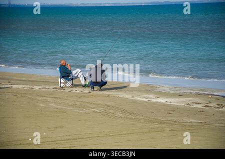 Deux hommes pêchant sur la côte de Sandy Beach Banque D'Images