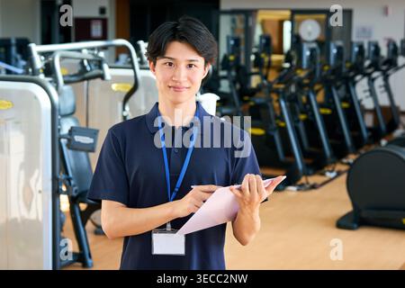 Portrait d'un jeune entraîneur japonais souriant regardant la caméra dans un gymnase Banque D'Images