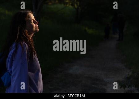 Jeune femme profitant de la lumière du coucher du soleil dans un cadre extérieur naturel Banque D'Images