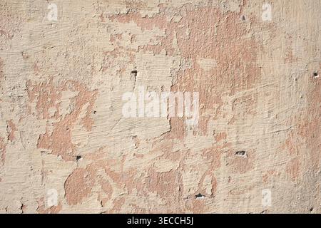 Vue de face macro d'un vieux mur altéré avec une peinture rose très écaillée Banque D'Images
