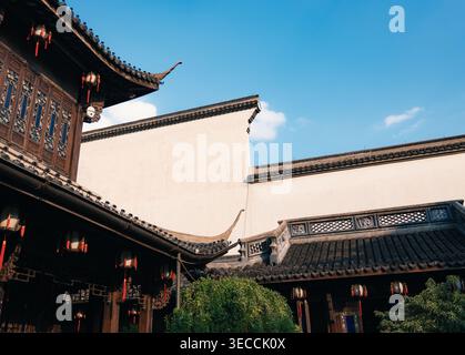Architecture chinoise traditionnelle avec toits ornés et lanternes rouges sous un ciel bleu clair Banque D'Images