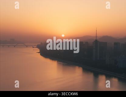 Beau coucher de soleil sur la rivière avec lueur orange reflétant sur l'eau et les ponts Banque D'Images