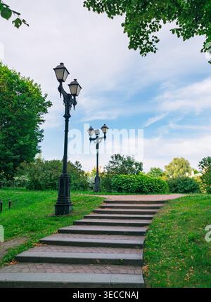 Beaux lampadaires historiques bordant un escalier en pierre dans un parc verdoyant par une journée d'été claire Banque D'Images