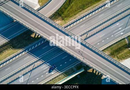 Système moderne d'échange routier avec plusieurs voies et véhicules en mouvement vus d'une vue aérienne pendant la journée ensoleillée Banque D'Images