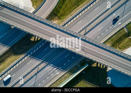 Système moderne d'échange routier avec plusieurs voies et véhicules en mouvement vus d'une vue aérienne pendant la journée ensoleillée Banque D'Images