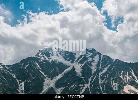 Majestueux sommets montagneux recouverts de neige avec des glaciers profonds sous un ciel bleu nuageux Banque D'Images