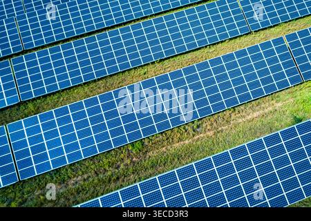 Vue aérienne de la vaste ferme solaire avec de nombreux panneaux photovoltaïques s'étendant à travers le paysage rural Banque D'Images