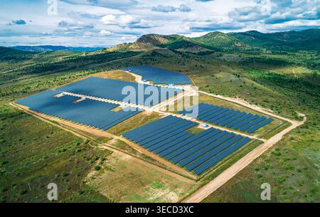 Vue panoramique aérienne de la vaste ferme solaire avec de nombreux panneaux photovoltaïques s'étendant à travers le paysage rural Banque D'Images