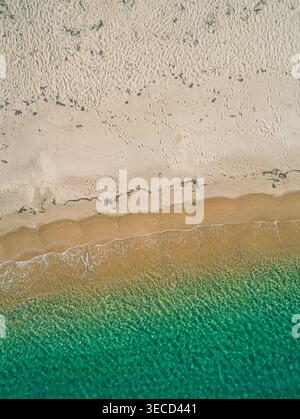 Les vagues de l'océan rencontrent doucement le littoral sablonneux, montrant des eaux turquoises claires et une plage dorée d'en haut Banque D'Images
