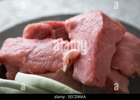 Morceaux de viande de porc crue avec des épices oignon et hachoir sur la table de cuisine pour la préparation de la cuisson Banque D'Images