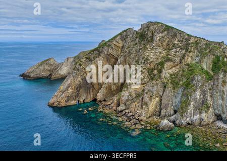 Vue aérienne du point de vue de silence Beach avec des falaises rocheuses spectaculaires et des eaux turquoises sous un ciel nuageux à Cudillero, Asturies, Espagne. Banque D'Images