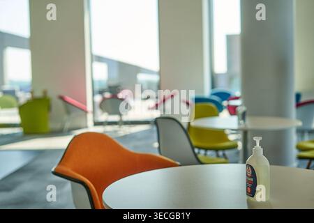 Intérieur de bureau moderne ou espace de détente d'entreprise mettant en vedette des chaises contemporaines colorées en orange, jaune, bleu, rouge et gris disposées autour du blanc Banque D'Images