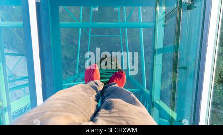 La photo des pieds du photographe avec le reflet en marchant sur la passerelle en verre transparent à Wat Phra That Pha Nago, Chiang Rai. Banque D'Images