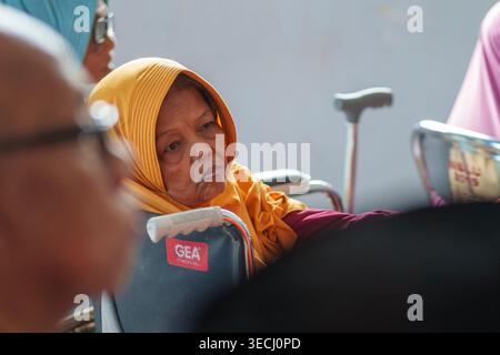 Une femme âgée en fauteuil roulant lors d'une visite sociale d'une organisation de femmes à PPSLU Mandalika, Mataram, Indonésie. Banque D'Images