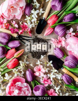 Les lettres de vue de dessus orthographe PEUVENT avec des fleurs et des outils de jardinage. Banque D'Images