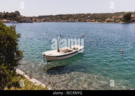 Petit bateau à rames en bois amarré dans l'eau cristalline de l'Adriatique Banque D'Images