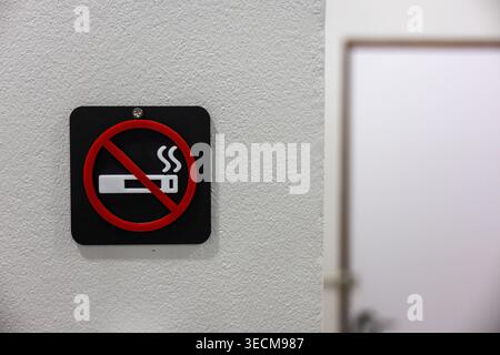 Sérieux panneau non fumeur avertissant les protocoles de santé publique et de sécurité pour un environnement intérieur monté sur un mur texturé blanc créant strict et cautio Banque D'Images