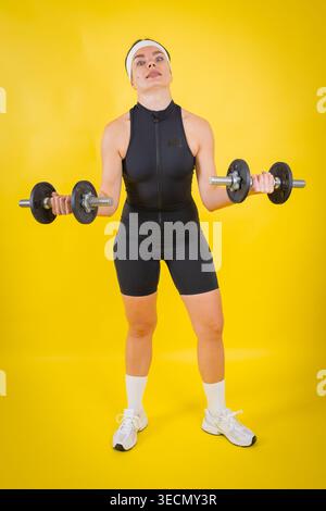 Femme exerçant avec des haltères faisant des boucles de biceps Banque D'Images