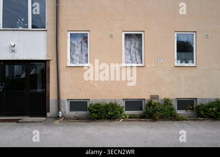 Façade de bâtiment simple et sans ornement avec trois fenêtres avec des rideaux couverts pour l'intimité. Nynashamn, comté de Stockholm, Suède, 25 mai 2025 Banque D'Images