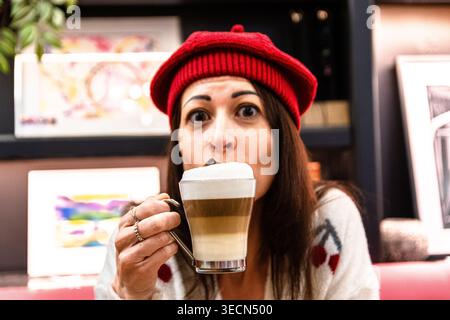 Femme appréciant un café latte dans un café confortable Banque D'Images