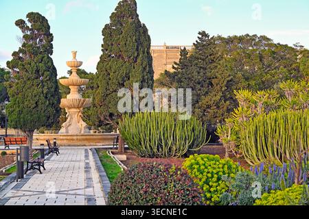 Une vue paisible sur les jardins botaniques Argotti à Floriana, Malte, avec une fontaine en pierre classique à gradins entourée de végétation méditerranéenne luxuriante Banque D'Images