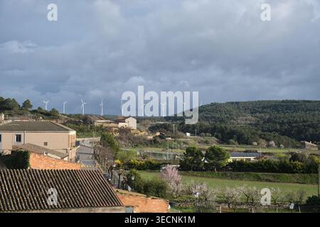 Éoliennes sur une colline surplombant un village rural espagnol sous un ciel nuageux. Fulleda, Catalogne, Espagne Banque D'Images