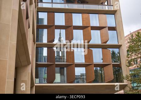 Vue rapprochée d'une façade de bâtiment contemporain présentant une architecture géométrique innovante avec de grandes fenêtres en verre et du métal angulaire couleur bronze Banque D'Images