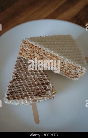 Deux morceaux de gâteau gaufré avec du lait condensé sur un bâton sur une assiette blanche. Dessert maison, plat Banque D'Images