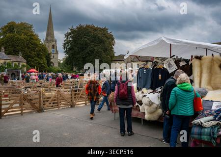 Étalage présentant des marchandises en laine, vendant des tapis et couvertures en peau de mouton (hommes femmes naviguant) - Masham Sheep Fair 2025, North Yorkshire Angleterre Royaume-Uni Banque D'Images