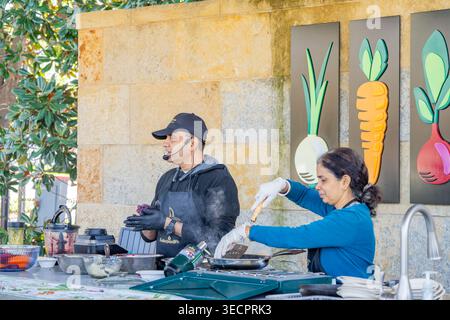 Texas, États-Unis, Mar 08, 2026 - Un chef masculin dans un tablier noir et une femme chef dans une chemise bleue cuisinent ensemble derrière un comptoir posé contre une pierre Banque D'Images