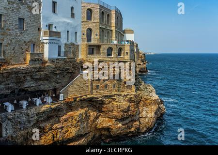 Polignano a Mare, avec ses bâtiments historiques perchés sur des falaises surplombant la mer bleue, et un restaurant chic niché dans une grotte. Polignano a Mare Banque D'Images