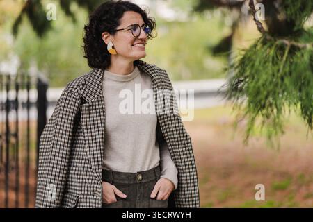 Femme mature dans une tenue élégante se tient à l'extérieur dans un cadre de ville, exsudant la confiance et l'élégance. Son sens de la mode moderne complète le vibrant ur Banque D'Images