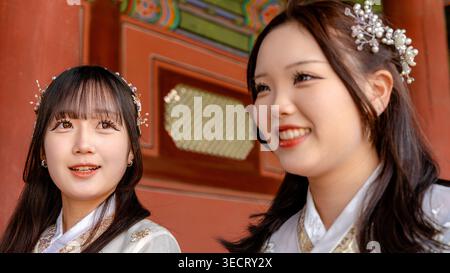 Deux femmes dans l'élégant hanbok, la robe coréenne traditionnelle, se tiennent devant l'architecture ornée du palais de Gyeongbokgung à Séoul, en Corée du Sud. Banque D'Images