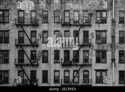 Une photographie vintage en noir et blanc d'une façade de bâtiment New-yorkais, présentant de nombreuses fenêtres, des échappées de secours et une architecture complexe, Captur Banque D'Images