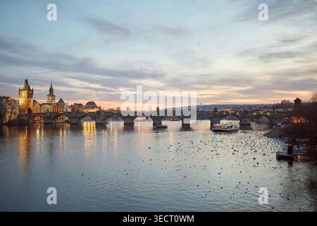Une vue imprenable sur le pont Charles sur la rivière Vltava au coucher du soleil à Prague. L'architecture gothique emblématique et les eaux tranquilles créent un s pittoresque Banque D'Images