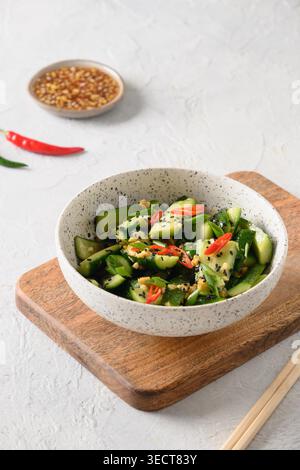 Salade épicée asiatique concombres cassés avec coriandre fraîche, gingembre sur fond blanc. Apéritif froid chinois populaire. Gros plan. Format vertical. Copier l'espace. Banque D'Images