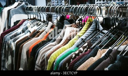 variété de pulls tricotés suspendus sur un rack, présentant une gamme de couleurs et de textures. Parfait pour la superposition hivernale, mettant l'accent sur le confort et le décontracté Banque D'Images