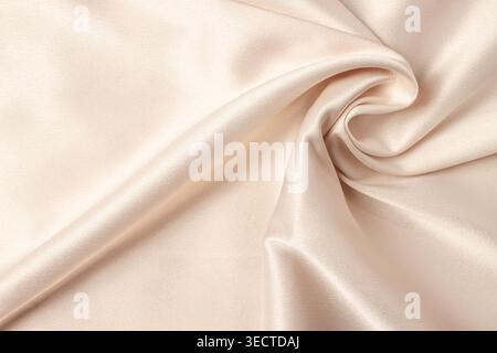 Silk atlas doux tissu de couleur beige tendre avec courbe brillante en macro de coin Banque D'Images