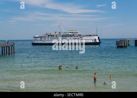 Oak Bluffs, Martha's Vineyard, ma, États-Unis-3 juillet 2025 : le ferry arrive au terminal de l'île et les gens nagent à la plage regardant le ferry. Banque D'Images