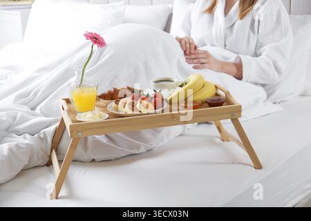 Femme mangeant délicieux petit déjeuner au lit à l'intérieur, gros plan Banque D'Images