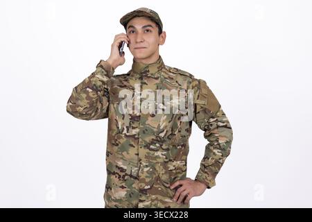 Homme en uniforme militaire parlant sur un smartphone en studio Banque D'Images